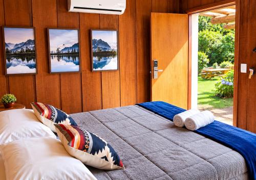 a bedroom with a bed with four pictures on the wall at Empório reserva da serra - Opções de chalés e Hidromassagem in Campos do Jordão