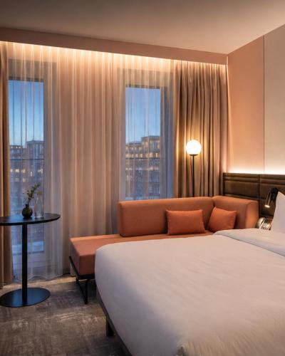 a hotel room with a bed and a couch and windows at Novotel Hamburg Central Station in Hamburg