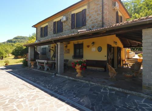 a yellow house with a porch with flowers on it at Scappo in Umbria, L'antico casale in Narni