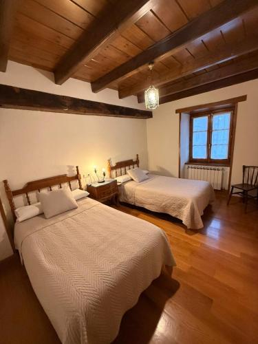 two beds in a room with wooden floors at La Posada Nueva in Viscarret-Guerendiáin