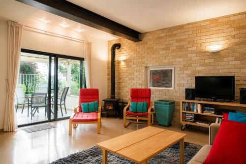 a living room with red chairs and a tv at Carmel Home Mount Seaview in Haifa