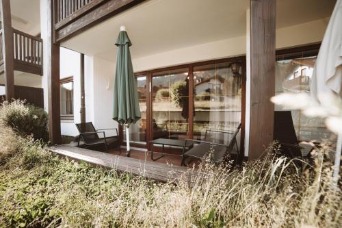 a patio with a green umbrella and chairs and a table at ALPEN STUDIO - moderne Ferienwohnung mit Bergblick & Südterrasse in Bad Hindelang in Bad Hindelang