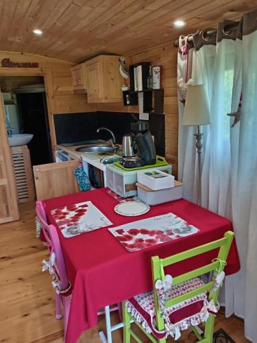 a kitchen with a table with a red table cloth at Roulotte Anaîs in Grandcourt