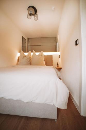 a bedroom with a large white bed with white pillows at ALPEN STUDIO - moderne Ferienwohnung mit Bergblick & Südterrasse in Bad Hindelang in Bad Hindelang