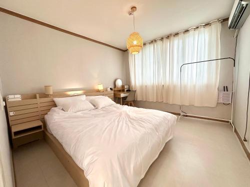 a bedroom with a large white bed and a window at Lagom villiage in Paegun-dong