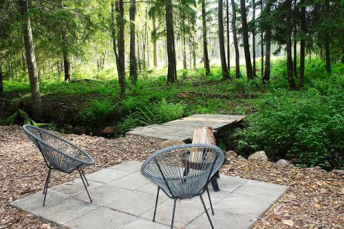 two chairs and a wooden table in a forest at PRIVAATNE Metsamajake SAUNAGA "VULIN" in Sigula