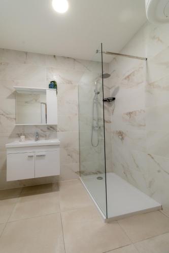 a white bathroom with a shower and a sink at Three Bedroom Qormi Home in Santa Venera