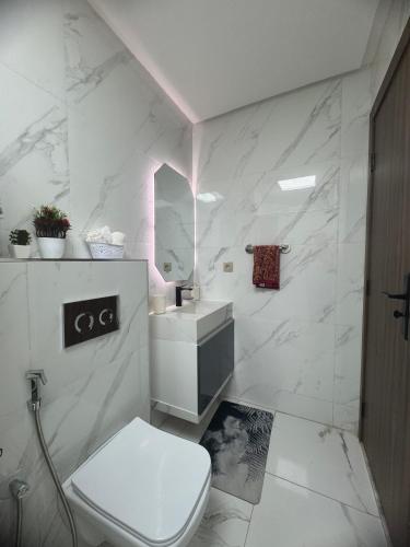 a white bathroom with a toilet and a sink at Mehdia plage in Kenitra