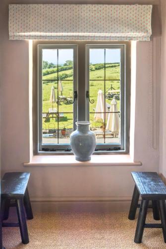 a vase sitting in a window with two benches at Botley Hill Farmhouse in Warlingham