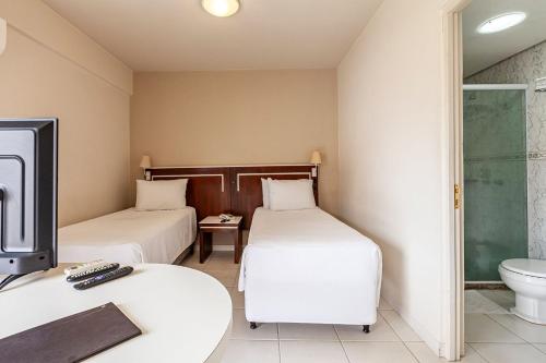 a hotel room with two beds and a toilet at Tri Hotel Executive Santa Maria in Santa Maria