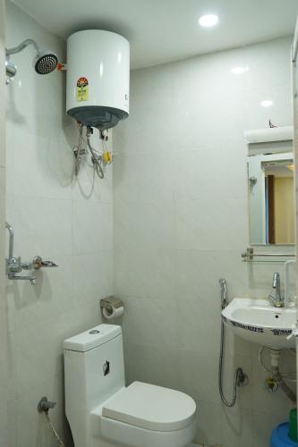 a white bathroom with a toilet and a sink at Hotel Kusum Palace in Kathmandu