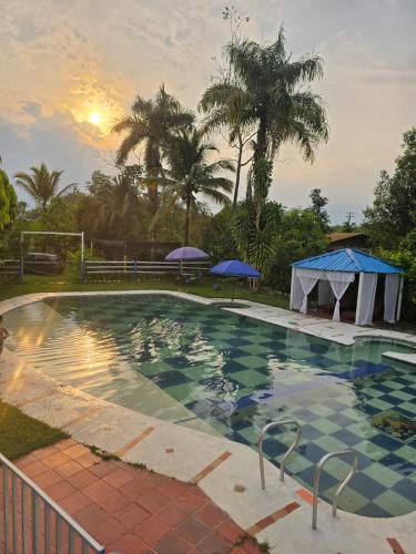 a swimming pool with a sunset in the background at Finca la santa in San Luis de Cubarral