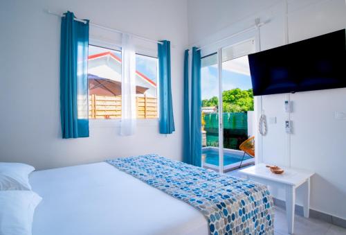 a white bedroom with a bed and a window at Villa piscine privée Grand-Bourg proche plage in Grand-Bourg