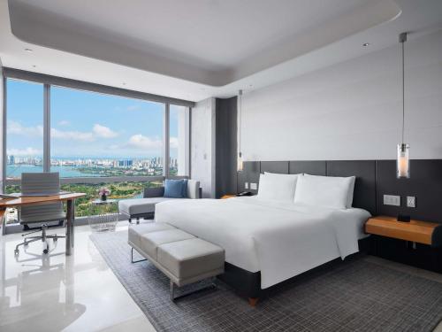 a bedroom with a large white bed and a desk at Sofitel Haikou in Haikou