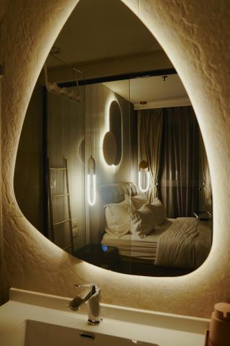 a bathroom with a mirror over a sink and a bed at Allenbeach TLV- Adults only - WE HAVE SHELTER in Tel Aviv