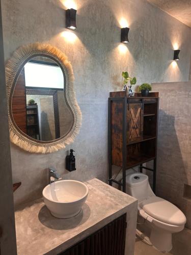 a bathroom with a sink and a toilet and a mirror at Aldea Pukna Tulum in Akumal