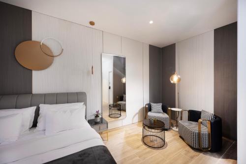 a bedroom with a bed and two chairs and a mirror at Allenbeach TLV- Adults only - WE HAVE SHELTER in Tel Aviv