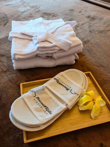 a wooden tray with towels and a plate and a flower at Studio Pleasant Tifolia in Jakarta