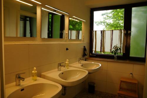 a bathroom with two sinks and two windows at Gästehaus am Sternberg in Gomadingen