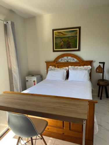 a bedroom with a large bed with a chair and a picture at Casa Temporada Aconchego e tranquilidade 3 in Bonito