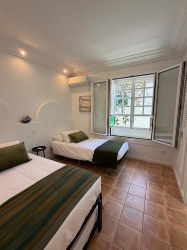 a bedroom with two beds and a window at Oasis de César- Arquitectura Manriqueña in Costa Teguise