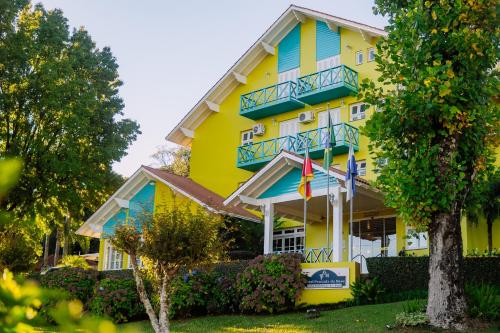 a yellow building with blue balconies and flags at Hotel Pousada da Neve in Nova Petrópolis