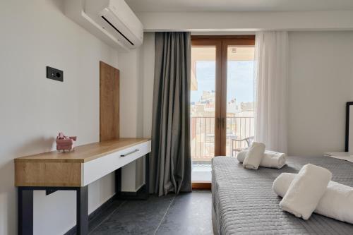 a bedroom with a desk and a bed and a window at Agia Triada Suites in Heraklio