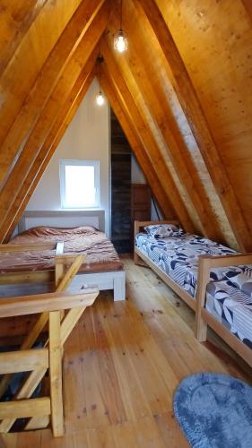 two beds in a attic room with wooden ceilings at Durmitor Holiday in Žabljak