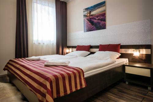 a bedroom with a large bed with a striped blanket at Apartman Mirka - Hotel Luka in Bešeňová
