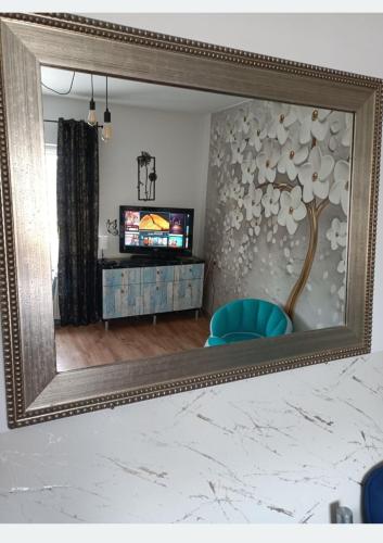 a mirror in a room with a tv and a blue chair at Centrum 3 łóżka Roosevelta 47 in Piła