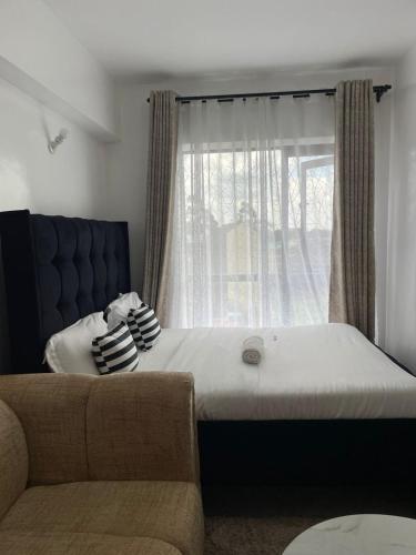 a bedroom with a bed and a window with a couch at Naivasha road Studio Opposite ILRI in Nairobi