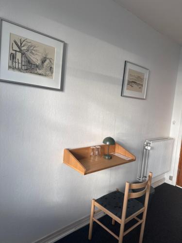 a wooden shelf on a wall next to a chair at carlsens hotel in Vesterø Havn