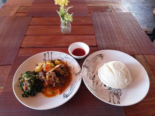 a table with two plates of food and a bowl of sauce at Tiptree Lodge in Livingstone
