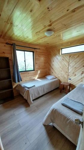 a bedroom with two beds in a wooden cabin at Cabañas Aguapiedras in Linares
