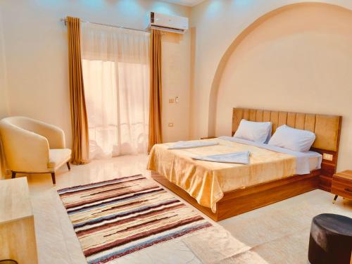 a bedroom with a bed and a chair and a window at Djorff Palace - Private villa & swimming pool & central location in Al Aqālitah