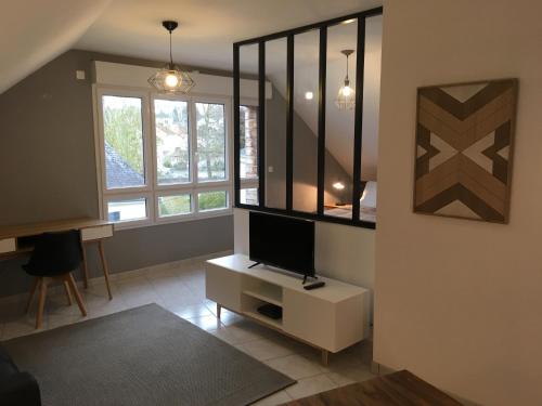 a living room with a tv on a cabinet and windows at Appart'Hôtel - Chateaubriant in Châteaubriant