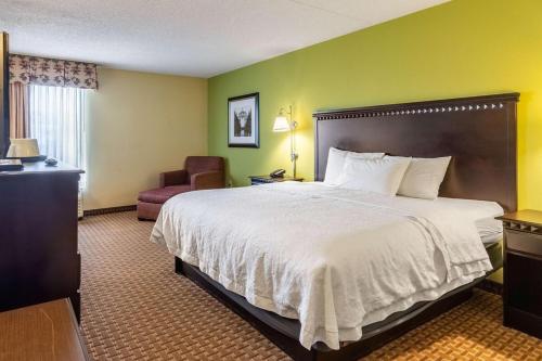 a hotel room with a large bed and a chair at Wingate by Wyndham Conway AR in Conway