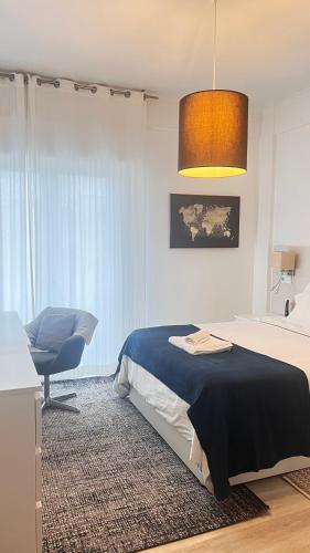 a bedroom with a bed and a chair and a lamp at Quarto com casa de banho privativo in Amadora