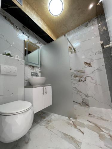 a white bathroom with a toilet and a sink at Villa Imperium Indoor & Outdoor Pool Riverfront Bjelašnica View in SJJ