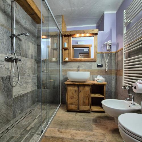a bathroom with a sink and a glass shower at M4478 Mollino Rooms in Breuil-Cervinia