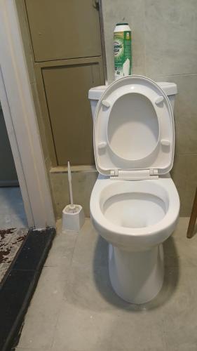 a white toilet in a bathroom with a brush at Naivasha road Studio Opposite ILRI in Nairobi
