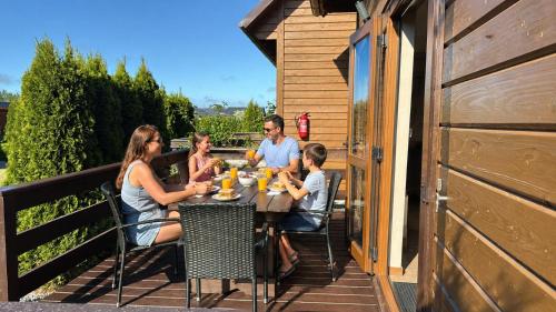 a group of people sitting at a table on a deck at Domki La Plata in Łeba