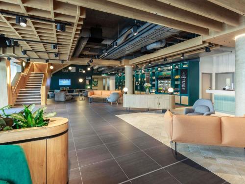 a lobby with furniture and stairs in a building at Novotel Cambridge North in Cambridge