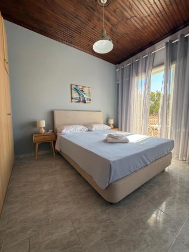 a bedroom with a large bed and a large window at Artemis Vassilikos in Vasilikos
