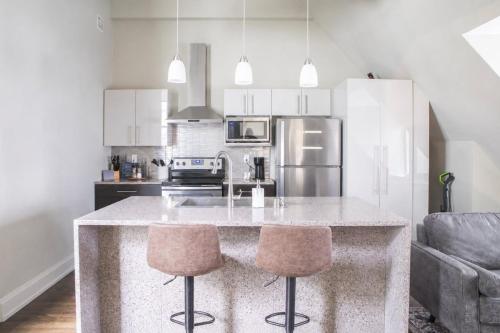 a kitchen with a large island with two bar stools at Downtown Luxury 1BR Loft · Walkable · Sleeps 4 in Milwaukee