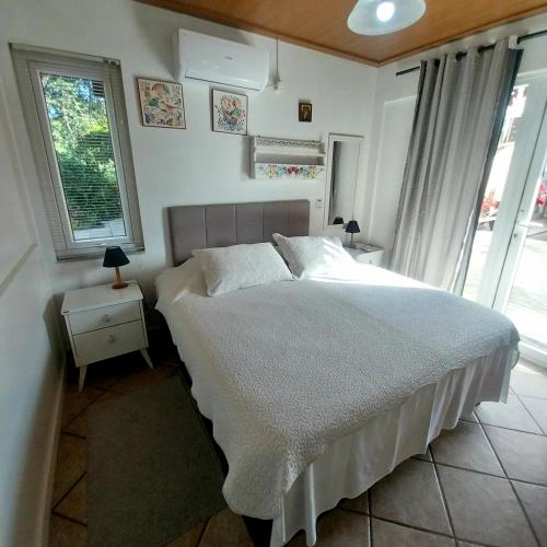 a bedroom with a white bed and a window at Pousada Agradável Pomerode in Pomerode