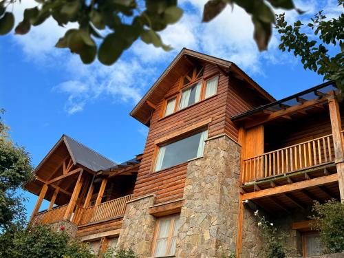 a wooden house with a balcony on top of it at Hostería Bärenhaus in San Martín de los Andes