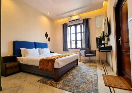 a bedroom with a bed and a desk and a window at Giovanni Suites in Bhopal