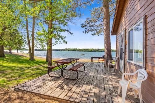 a wooden deck with a picnic table and chairs on a house at Cabin #9 2BR 1BA Timberlane Resort in Park Rapids