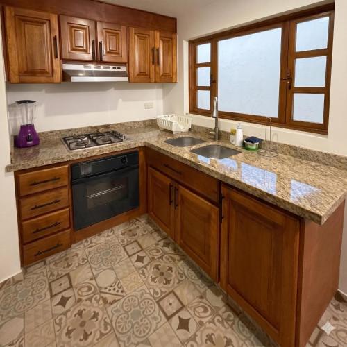 a kitchen with wooden cabinets and a sink and a window at Casa Hotel Cenit in Villa de Leyva